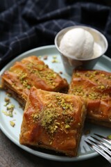 Delicious baklava with crushed nuts and ice cream on wooden table, closeup