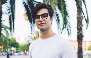 Portrait of handsome caucasian male photographer in trendy casual wear and spectacles making photos outdoors, skilled 20s man amateur enjoying time on hobby taking pictures on leisure in city