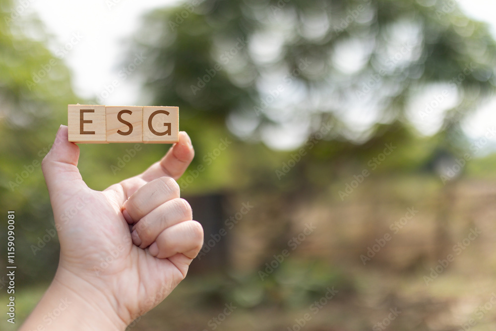 Poster one hand holds a wooden block with the letters esg on it. the letters are arranged in a row. nature 