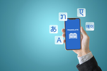 A person holds a phone with a blue screen with a translation text. The screen has multilingual book icons.