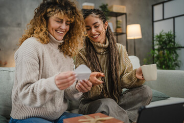 two female friends read greeting card while have video call on tablet