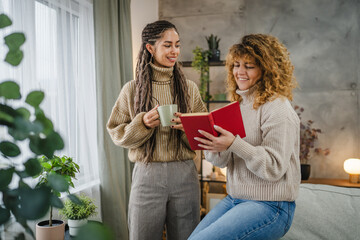 two caucasian female friends read a book together leisure activity