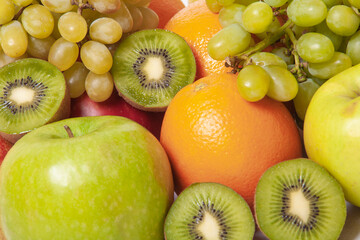 A vibrant assortment of kiwi, apples, oranges, and grapes in close-up
