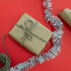 Packing of New Year's gifts Gift, twine, paper and tinsel on a red background.