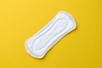 Women's sanitary napkin on bright yellow background, hygiene product concept
