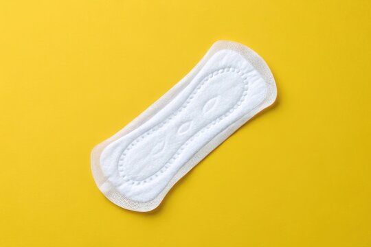 Women's sanitary napkin on bright yellow background, hygiene product concept