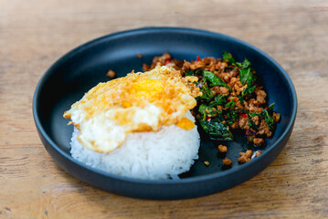 Spicy fried pork with basil leaves, the famous traditional Thai food served with jasmine rice and fried egg.