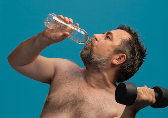 Elderly man exercising with dumbbell while staying hydrated during workout session