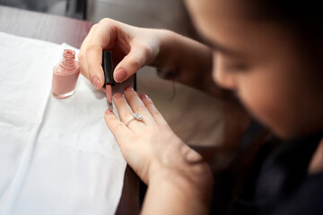 Woman paints her nails a beige color