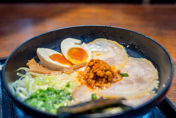 Japanese noodle tonkotsu soup ramen with egg and pork in black ramen bowl for Japanese food style.
