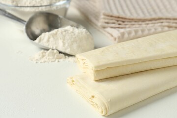 Raw puff pastry dough on white table, closeup. Space for text