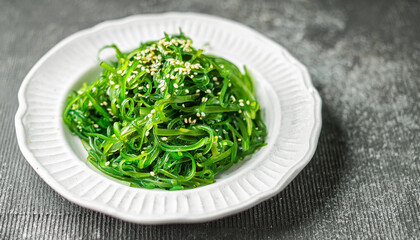 Green seaweed salad in white plate. Tasty food. Delicious and healthy dish. Close-up