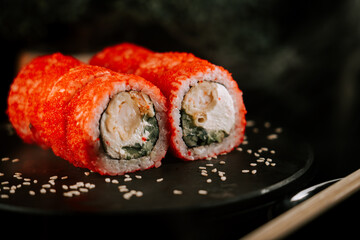 Fresh red sushi on a black board with chopsticks on a dark background. Set of rolls with caviar....