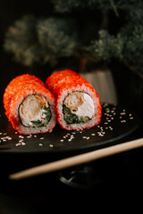 Fresh red sushi on a black board with chopsticks on a dark background. Set of rolls with caviar. Sushi concept