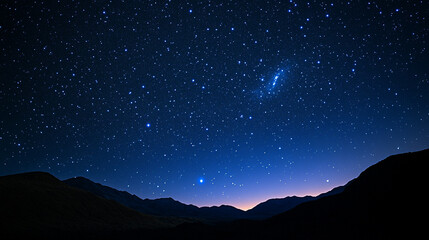 Stars illuminate a dark sky over mountain silhouettes at dusk