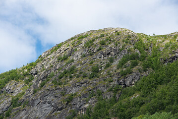 Beautiful Norwegian mountain landscape with a mountain peak against a blue sky. Mountain with green...