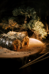Freshly Made Sushi Roll Garnished With Herbs on a Wooden Plate in a Serene Setting During Evening Hours