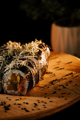 Sushi Rolls Garnished With Sprouts Served on a Wooden Platter in a Dimly Lit Setting