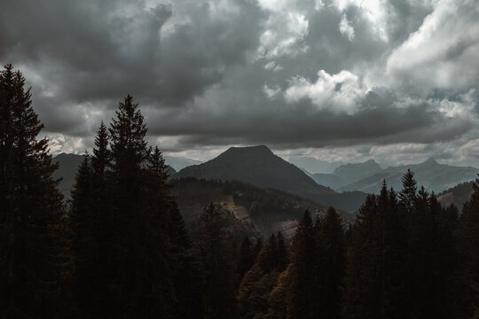 Drammatic grey clouds over forest with mountains
