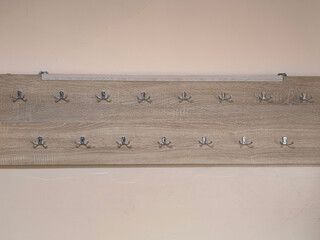 A wooden board with many hooks on it. The board is beige and has a greyish tone.