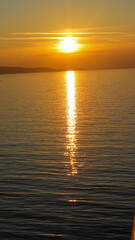 Obraz premium Foto vertical do pôr do sol no Mediterrâneo, capturando a beleza das cores vibrantes e o reflexo do sol sobre as águas calmas do mar