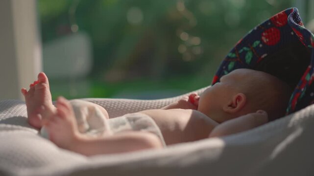 A newborn baby rests in a baby cocoon near an open sunlit window, absorbing natural sunlight for a healthy dose of vitamin D. A serene moment emphasizing the importance of sunbathing for newborn's