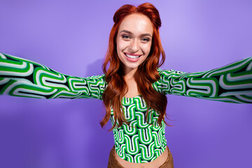 Cheerful young woman with stylish red hair posing against a violet background, wearing a trendy...