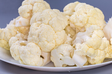 Heap of raw cauliflower pieces on dish close-up