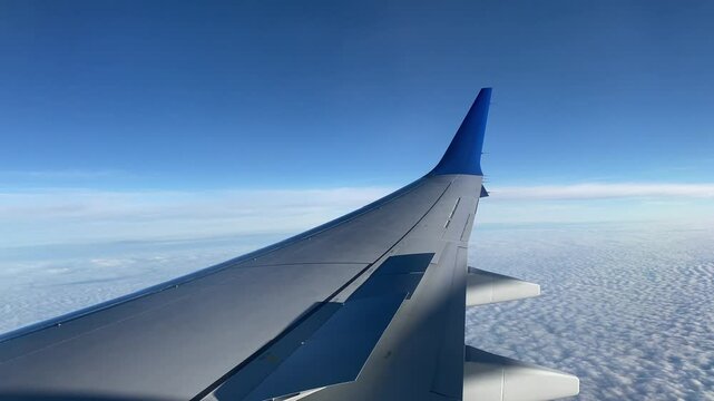Airplane Wing During Turbulence Above Clouds with Blue Sky