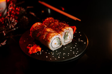Delicious fresh sushi rolls with ginger and herbs illuminated by soft red light on a dark background