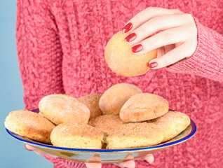 A woman's hand takes a curd cookie from a cookie dish.