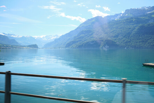 Scenic view of Lake Brienz in Switzerland, surrounded by majestic mountains reflecting on the clear turquoise water. A tranquil and picturesque landscape captures natural beauty.