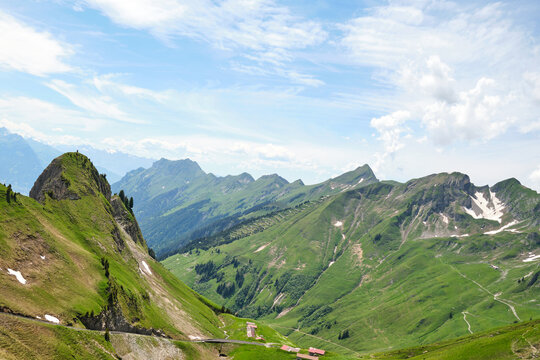 Breathtaking view of green mountains in Brienz, Switzerland, showcasing rolling hills and rugged peaks under a blue sky, perfect for nature lovers and hikers.