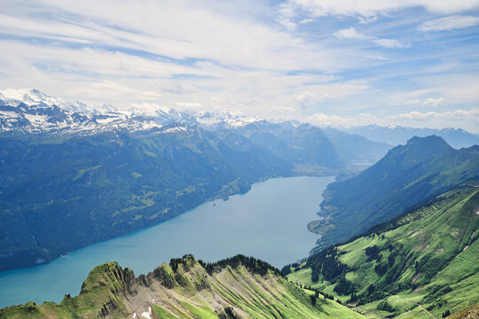 Breathtaking view of Lake Brienz surrounded by lush green hills and snow-capped mountains in Switzerland. A perfect landscape for nature lovers.