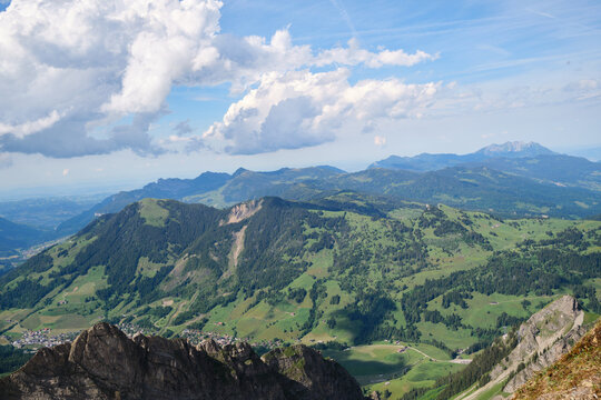 Spectacular panoramic view of Swiss Alps showcasing lush green valleys and rugged mountain peaks under a vibrant sky. Ideal for nature enthusiasts and photographers.