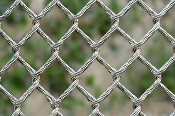 Fototapeta premium Metal wire mesh fence with natural background, showcasing intricate patterns and textures