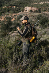 Hunter using walkie talkie with rifle on shoulder