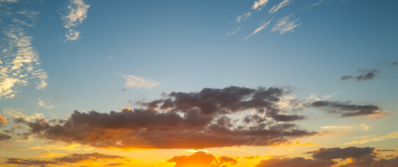 Sunset background. Dramatic majestic scenery sunset. Sky with clouds in sunset sky light background. Sunrise with clouds in various shapes. Calm sunset sky and sun through clouds over.
