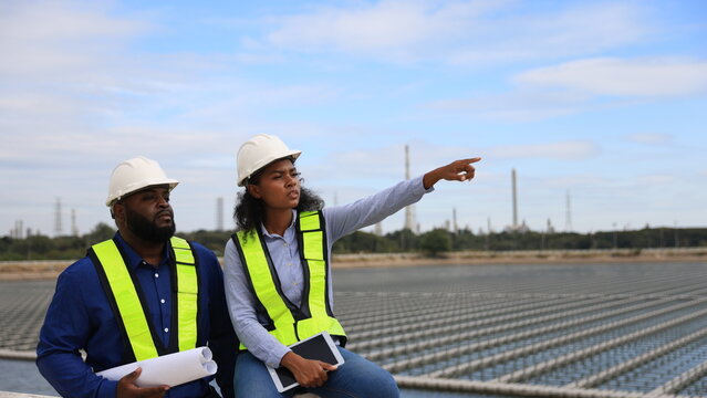 Black persons of Electrical Engineers or workers work on-site Floating solar panels or solar cell Platform systems on the lake.