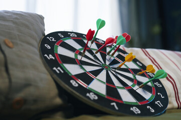 Close-up of dartboard with darts on sofa in the room for leisure games