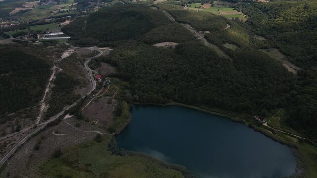 Drone shot of green landscape of small lake between lush forested hills and village in Sakarya