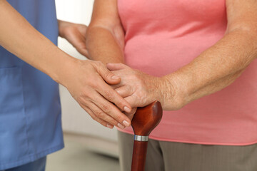 Healthcare worker supporting senior patient indoors, closeup