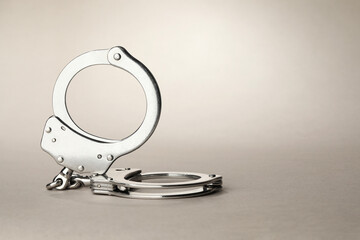 Metal chain handcuffs on light grey background, closeup. Space for text