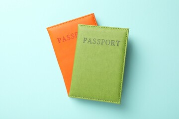 Passports in color covers on light blue background, top view