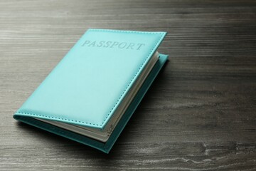 Passport in turquoise cover on wooden table, closeup