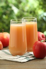 Tasty apple juice and fresh fruits on wooden table against blurred background