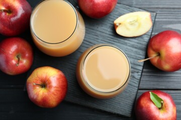 Refreshing apple juice in glasses and fruits on black wooden table, flat lay