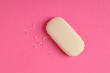 One eraser and scraps on pink background, top view