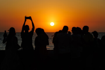 A group of people with only their silhouettes visible, standing against the sunset on the walls of Cartagena.