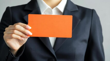 Business professional holding bright orange card against neutral background